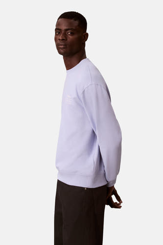 Pull-over marron avec col rond de Calvin Klein, avec une subtile impression textuelle et porté avec un pantalon noir, en vue latérale.