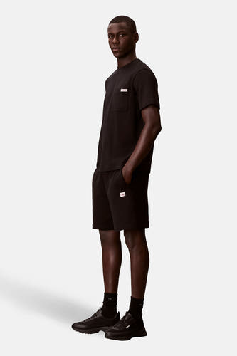 Short noir de Calvin Klein, avec un petit logo sur la jambe de pantalon, associé à des chaussettes noires et des chaussures.