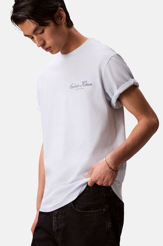 T-shirt bleu à manches courtes de Calvin Klein, avec manches retroussées et un bracelet argenté.