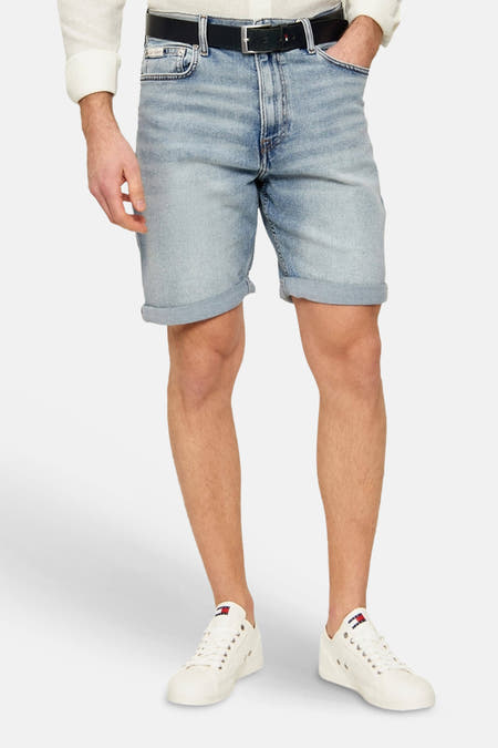 Lichtblauwe denim jeansshort van Calvin Klein met opgerolde zomen, gestyled met een donkere riem en witte sneakers.