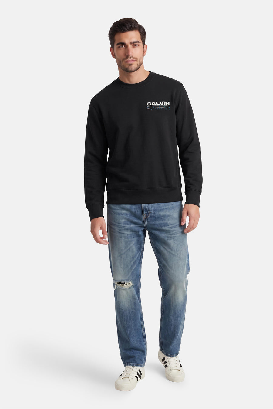 Zwarte ronde hals sweater van Calvin Klein met wit logo op borst, gedragen met blauwe jeans en witte sneakers, front view