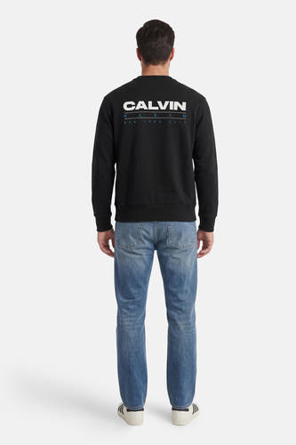 Zwarte ronde hals sweater van Calvin Klein met witte logo op rug, gedragen met blauwe jeans, achterkant weergegeven