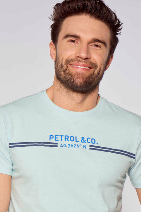 Lichtblauwe korte mouwen T-shirt van Petrol Industries® met blauw logo en strepen, gedragen door een glimlachende man, close-up voorzijde.