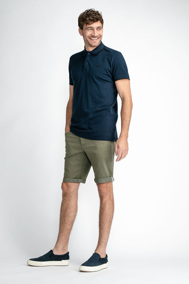 Groene jeansshort met opgerolde pijpen van Petrol Industries®, gedragen met donkerblauw poloshirt en sneakers, front view