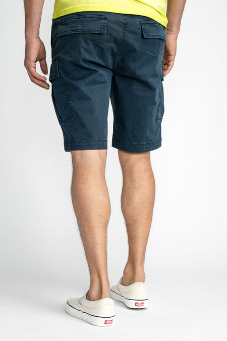 Blauwe cargo shorts van Petrol Industries®, achterkant met zakken, gedragen met geel shirt en witte sneakers