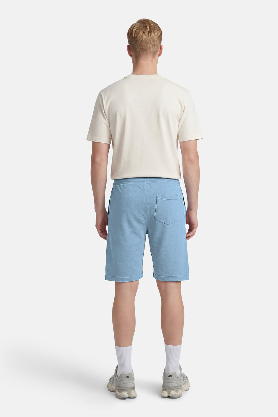 Blauwe short van Petrol Industries, gezien van achteren, met een enkele achterzak en gecombineerd met een crèmekleurig T-shirt.