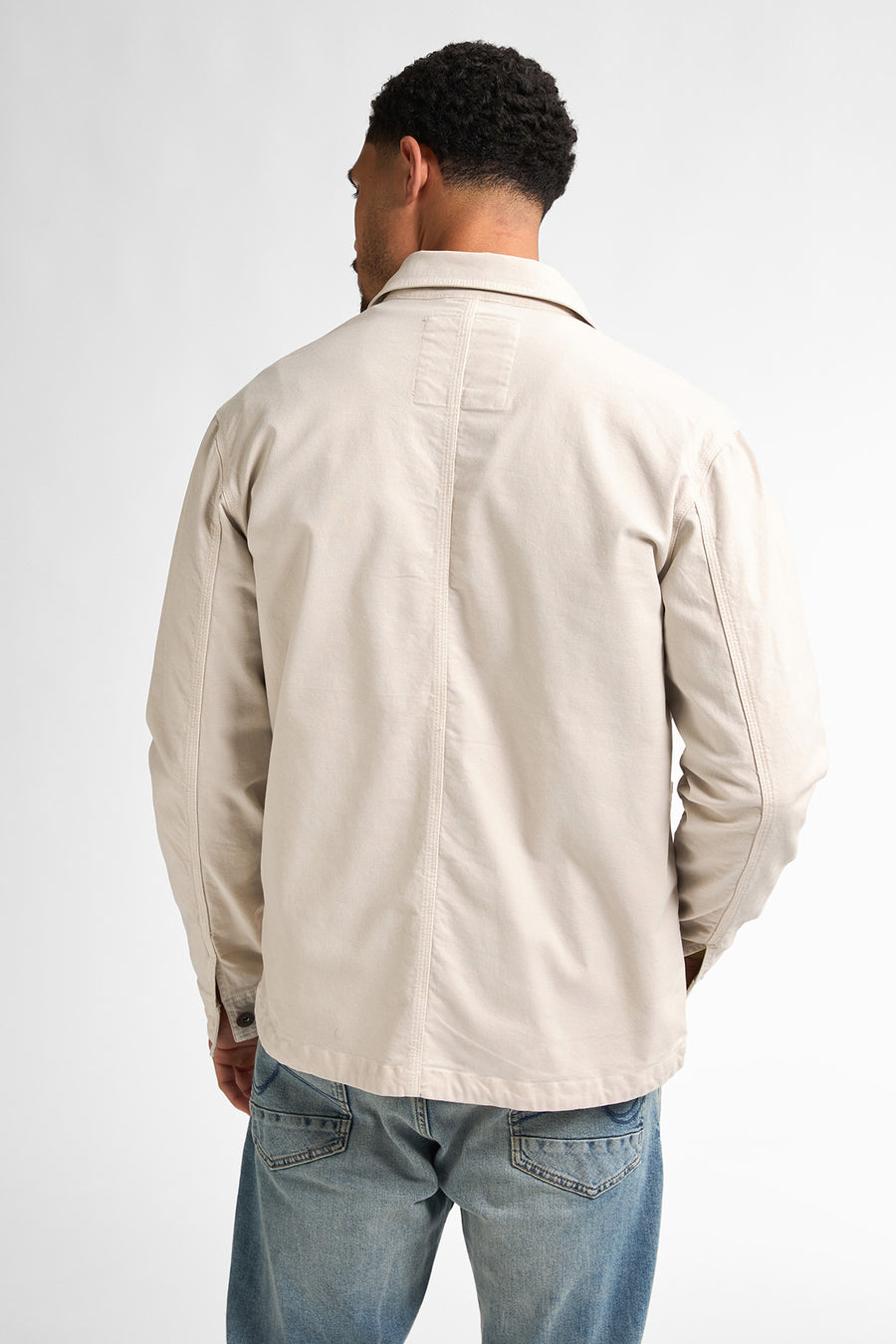 Man, achterkant, beige jas, blauwe jeans.