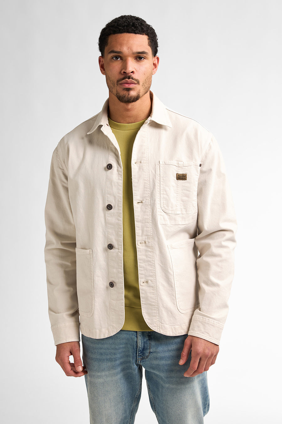 Man met beige jas en blauwe jeans.