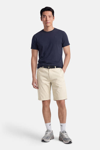 Ecru short van Petrol Industries®, met een zwarte riem en witte sokken met sneakers.
