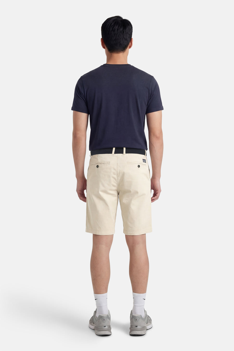 Ecru short van Petrol Industries®, gezien van achteren, gecombineerd met een donkerblauw t-shirt, een zwarte riem, witte sokken en grijze schoenen.
