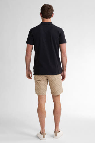 Beige short van Petrol Industries met een grafisch patroon, gecombineerd met een zwart poloshirt en witte sneakers.