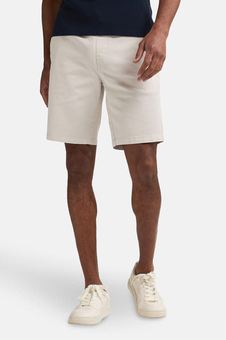 Beige court de Petrol Industries®, avec une ceinture élastique et des baskets blanches.