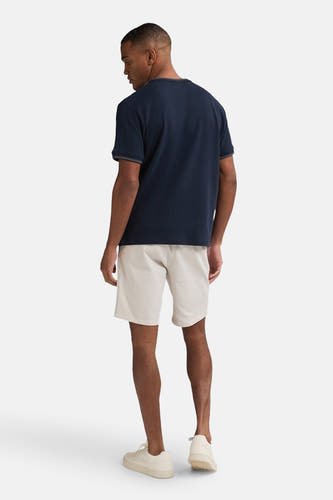 Beige short van Petrol Industries®, compleet met een donkerblauw T-shirt en crèmekleurige sneakers.