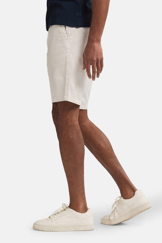 Beige short van Petrol Industries, zijwaarts getoond, gecombineerd met effen crèmekleurige sneakers en een donkerblauw shirt.