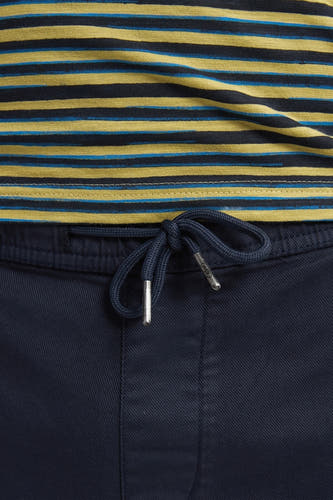 Blauwe short van Petrol Industries met een geknoopte trekkoord en een gestreept shirt gedeeltelijk zichtbaar.