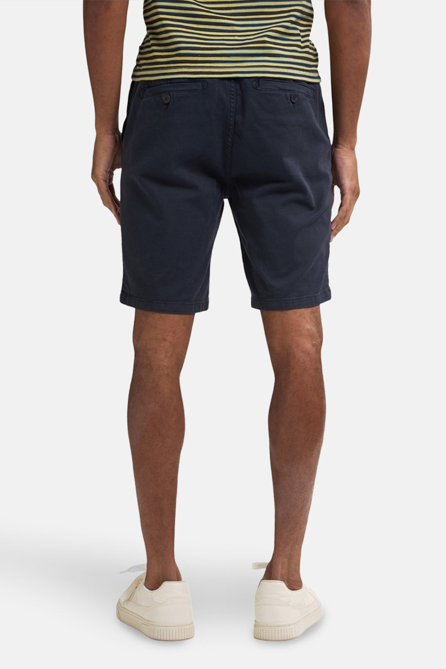Blauwe short van Petrol Industries, met achterzakken, gedragen met een gestreept shirt en crèmekleurige schoenen.
