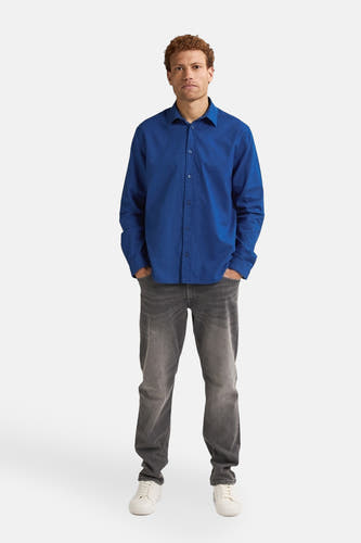 Blauw overhemd met lange mouwen van Petrol Industries, gedragen met grijze jeans en witte schoenen.
