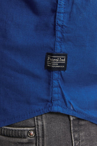 Blauw overhemd met lange mouwen van Petrol Industries, close-up van het label en een grijze broek.
