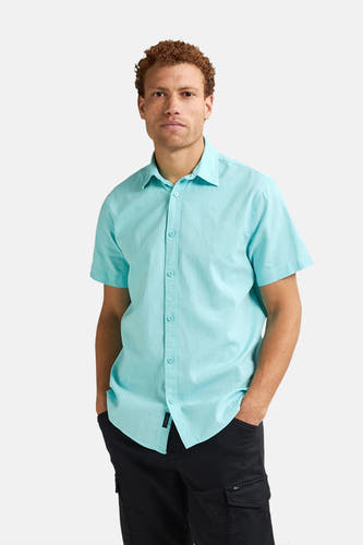Turquoise hemd met korte mouwen van Petrol Industries, met knoopsluiting en gedragen met zwarte broek.