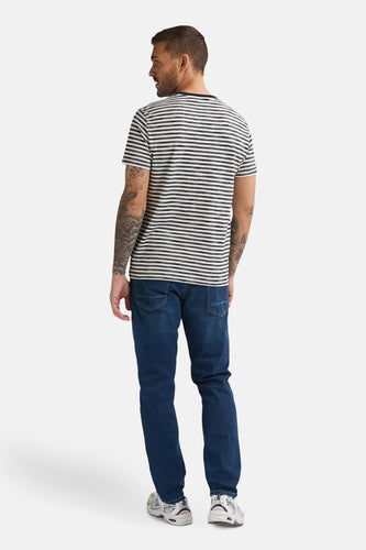 Man met gestreepte top en blauwe jeans.