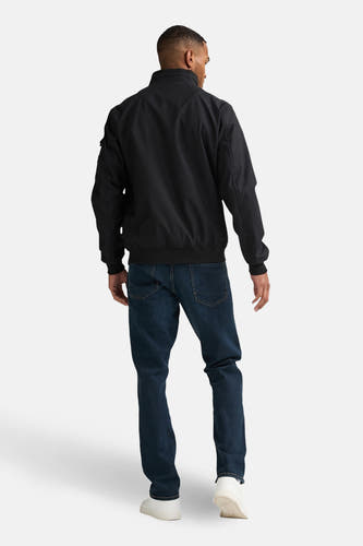 Zwarte korte jas van Petrol Industries®, gezien van achteren, gecombineerd met blauwe jeans en witte schoenen.

