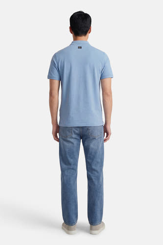 Blauw poloshirt van Petrol Industries®, achterkant gezien, gedragen met jeans en grijze schoenen.