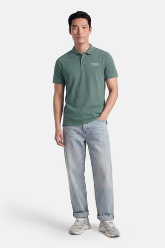 Groene polo van Petrol Industries met korte mouwen en een logo op de borst, gedragen met lichte jeans en sneakers.
