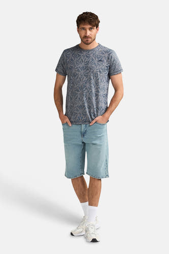 Short en jean bleu clair de Petrol Industries®, combiné avec un t-shirt imprimé et des baskets blanches avec chaussettes.