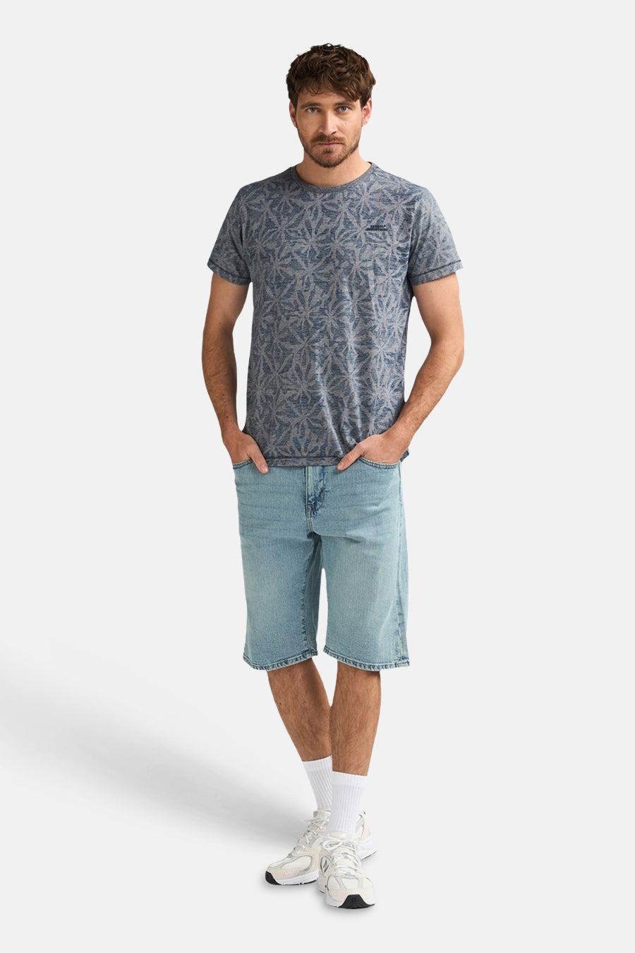 Short en jean bleu clair de Petrol Industries®, combiné avec un t-shirt imprimé et des baskets blanches avec chaussettes.