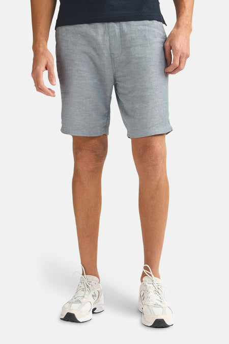 Blauwe short van Petrol Industries® met een geweven textuur, gecombineerd met witte sportschoenen.
