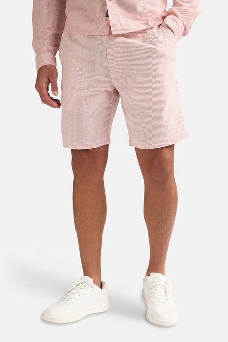 Roze gestreepte short van Petrol Industries®, gedragen door een model met bijpassend overhemd en witte sneakers.