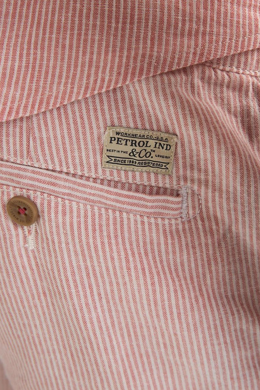 Roze gestreepte short van Petrol Industries, met beige textiellabel en bruine knoop.