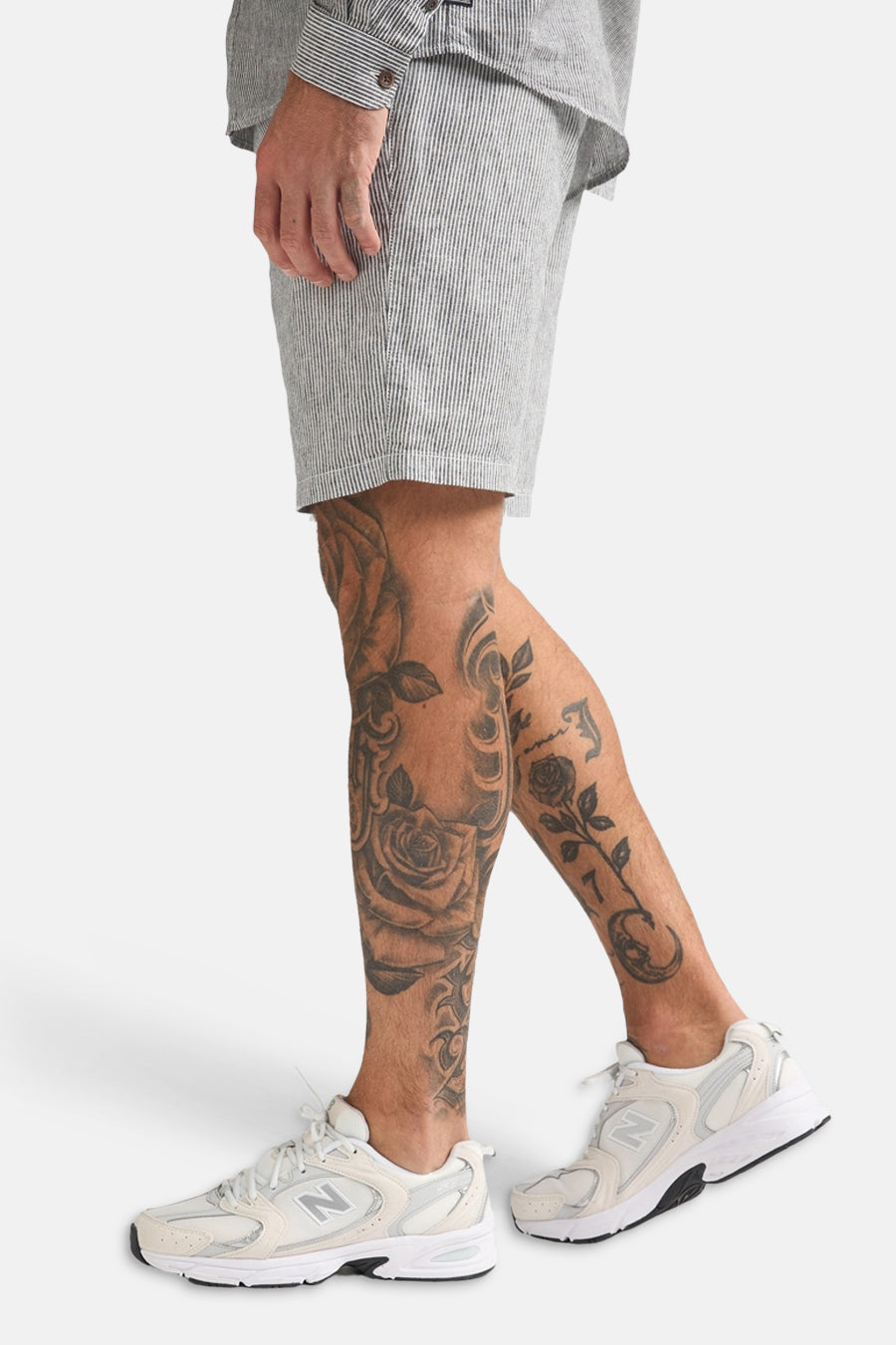 Short rayé gris et blanc de Petrol Industries, porté par un homme avec des tatouages et des baskets blanches.