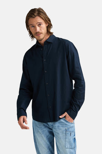 Blauw overhemd met lange mouwen van Petrol Industries®, gedragen met jeans en nonchalante haarstijl.