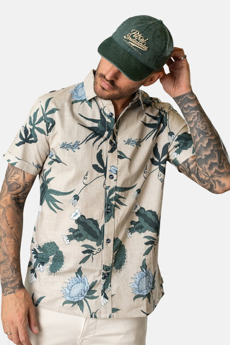 Multikleurig overhemd met korte mouwen van Petrol Industries, met een botanische print en gedragen met een groene pet.
