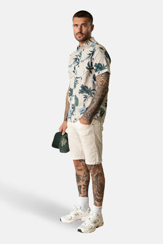 Multikleurig overhemd met korte mouwen van Petrol Industries, met een bloemenpatroon en gedragen met witte shorts en sneakers.
