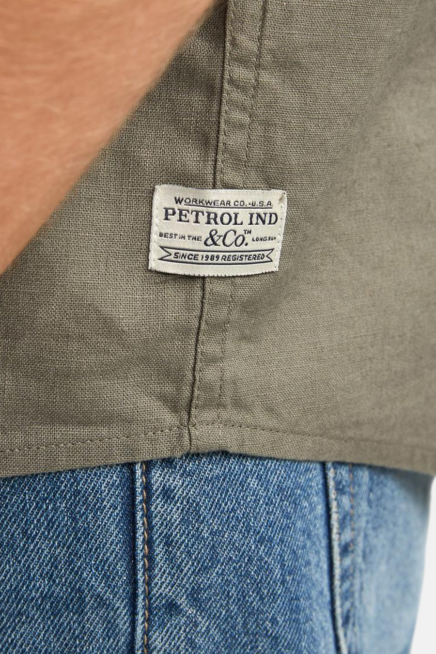 Chemise verte de Petrol Industries avec une étiquette tissée et un jean visible.