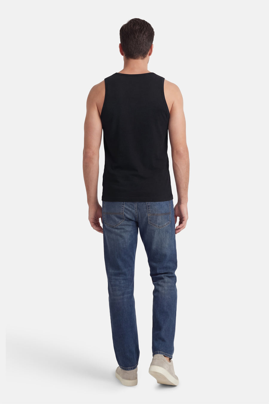 Zwarte tanktop van Petrol Industries, met zichtbare schouders, gecombineerd met blauwe jeans en grijze schoenen, gezien van achteren.
