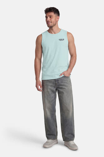Groene tanktop van Petrol Industries, met een print op de borst, gecombineerd met een losse jeans en sneakers.