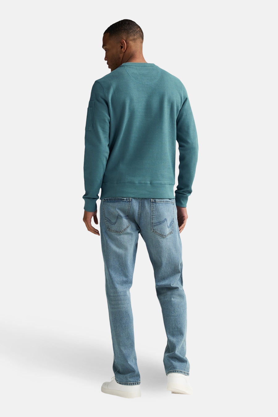 Pull-over vert de ronde collet Petrol Industries, vu d' derrière ar combiné avec un jeans et des chaussures blanches.