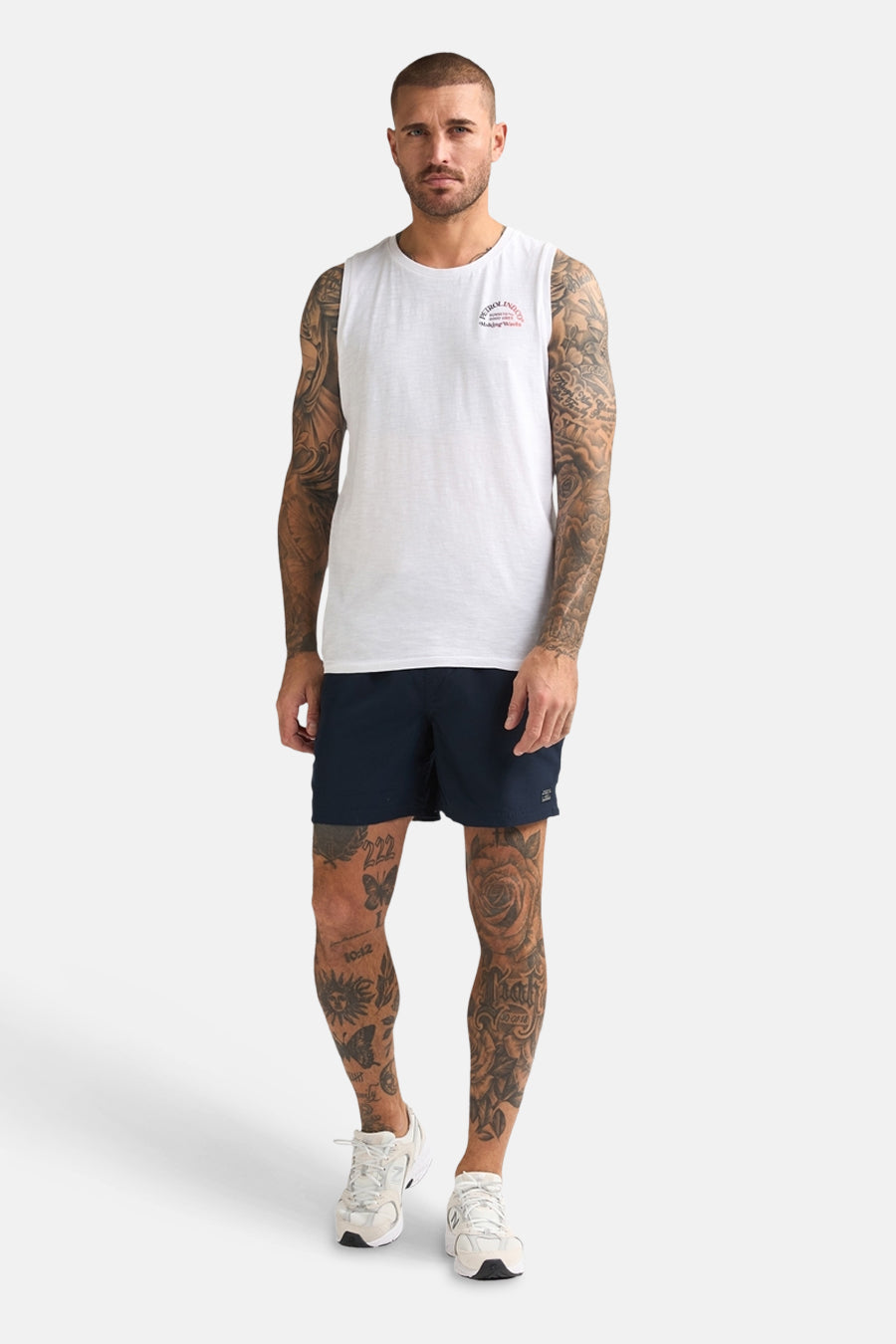 Blauwe zwemshort van Petrol Industries met tattoos op de benen en witte sneakers.