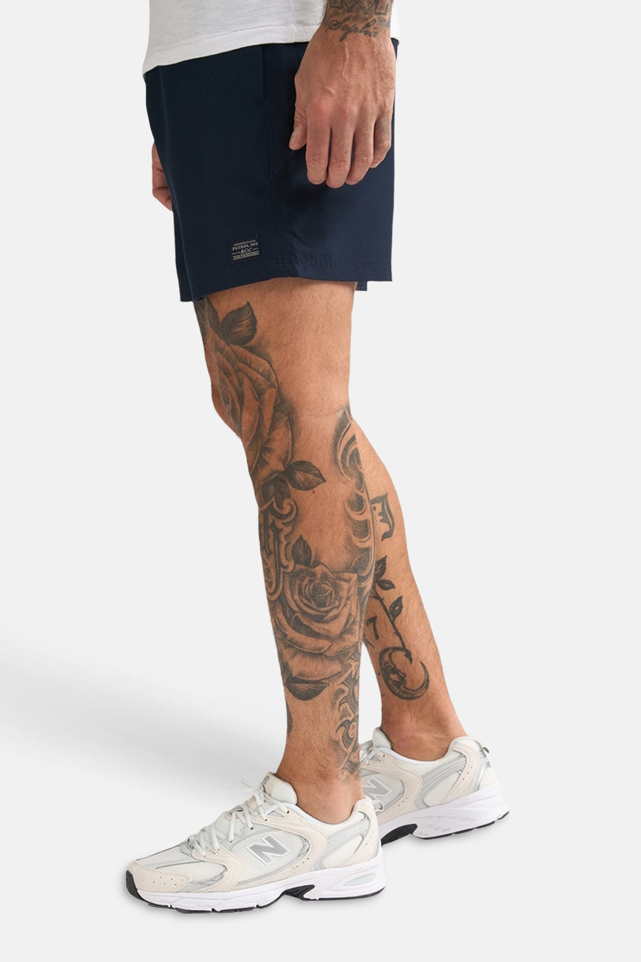 Blauwe zwemshort van Petrol Industries, met korte pijpen en verder een getatoeëerde man met witte schoenen.
