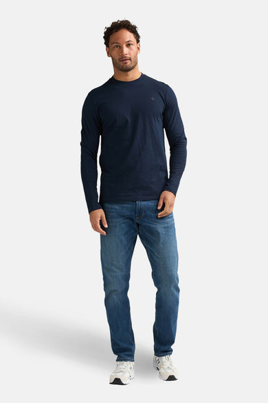 T-shirt bleu à manches longues de Petrol Industries®, porté avec un jean bleu et des baskets blanches.