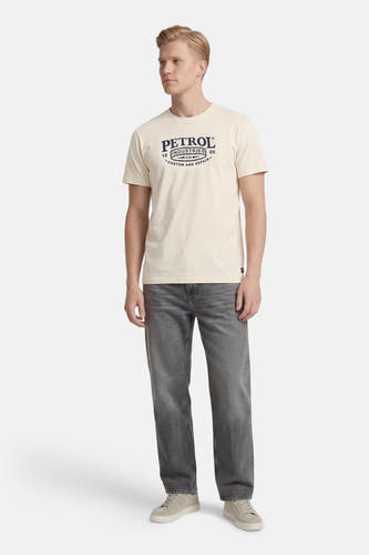 Ecru T-shirt met korte mouwen van Petrol Industries, met een logo-opdruk en gedragen met een grijze jeans en crèmekleurige sneakers.