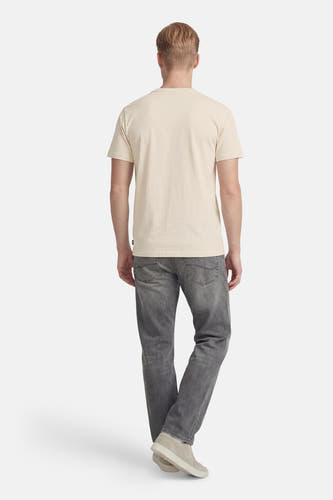 Ecru T-shirt met korte mouwen van Petrol Industries®, gezien vanaf de achterkant, met een effen kleur en gedragen met grijze jeans en beige schoenen.