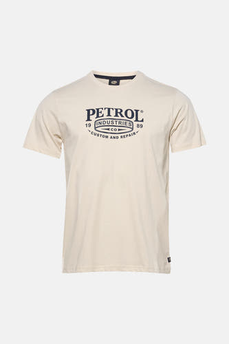 T-shirt écru à manches courtes de Petrol Industries, avec un imprimé logo et porté avec un jean gris et des baskets de couleur crème.