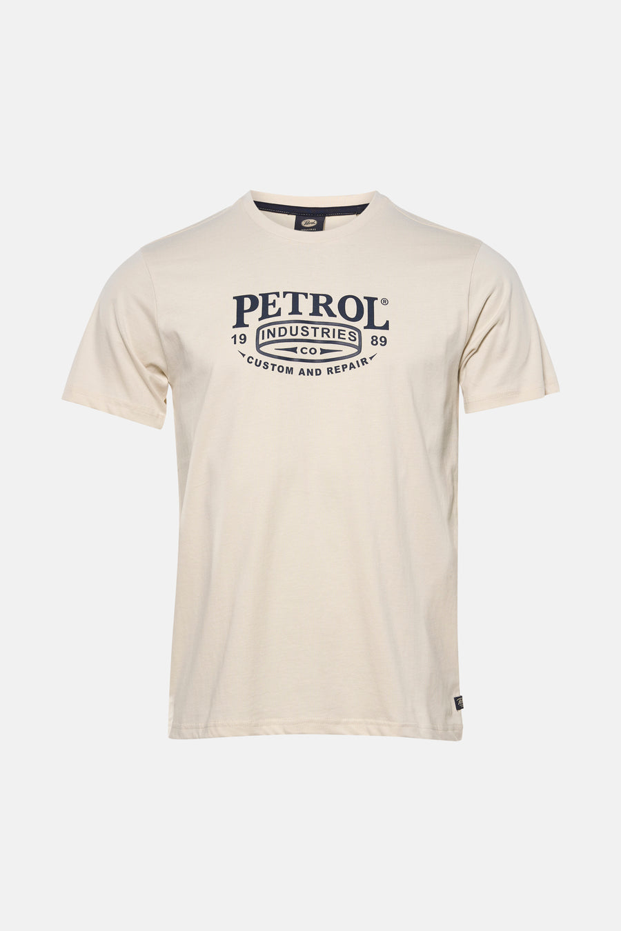 T-shirt écru à manches courtes de Petrol Industries, avec un imprimé logo et porté avec un jean gris et des baskets de couleur crème.