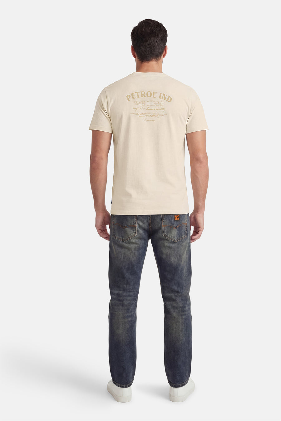Ecru T-shirt met korte mouwen van Petrol Industries, met tekstprint op de rug en gedragen met jeans en witte sneakers.

