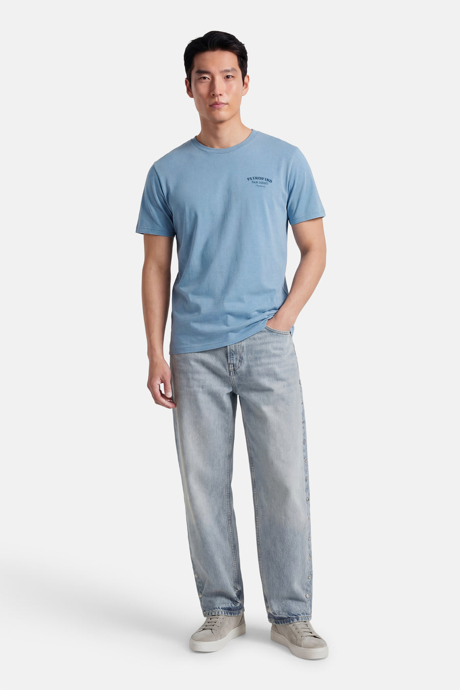 Blauw T-shirt met korte mouwen van Petrol Industries, met een kleine print op de borst, gedragen met een lichte jeans en grijze schoenen.
