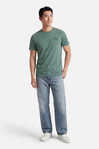 Groen T-shirt met korte mouwen van Petrol Industries, met kleine print, gedragen met blauwe jeans en witte sneakers.
